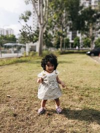 Full length of cute girl standing against plants at city gardens
