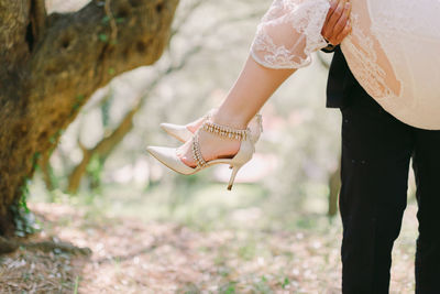 Midsection of groom lifting bride outdoors