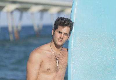 Portrait of shirtless man standing in sea against sky