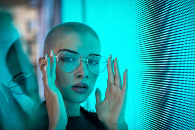 Portrait of young woman with shaved head standing against abstract backgrounds