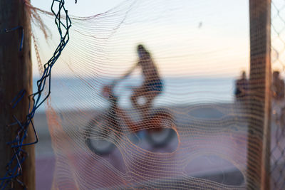 Silhouette of cyclists and people walking on the edge of a beach against sunset. 