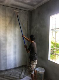 Rear view of man working at window