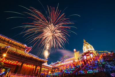 Low angle view of firework display over buildings at night