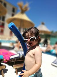 Portrait of baby boy wearing swimming goggles at resort on sunny day