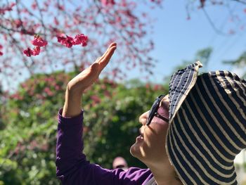 Portrait of woman with arms raised on plant