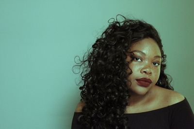 Close-up portrait of young woman against blue background