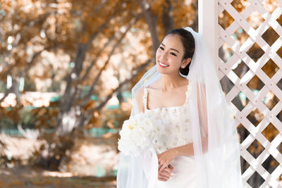 Smiling bride holding bouquet looking away