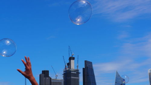Low angle view of bubbles against modern buildings in city