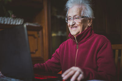 Smiling senior woman using laptop while sitting at home