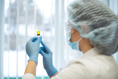 Rear view of doctor holding syringe in hospital