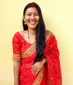 Portrait of a smiling young woman standing against wall