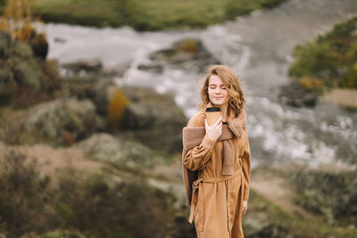 A pretty girl enjoys solitude drinks coffee walks in the autumn forest in nature in fall