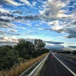 Cars on road against cloudy sky