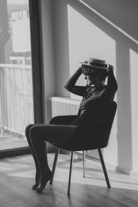 Side view of woman sitting on table at home