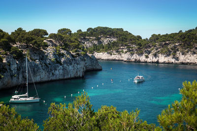 Boats sailing in sea against clear blue sky