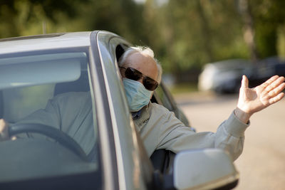 Senior man wearing anti virus mask are driving in a car during the covid-19 pandemic