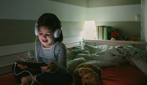 Young man using mobile phone while sitting on bed at home