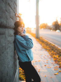 Rear view of young girl standing on footpath against the wall in maple fall autumn canada