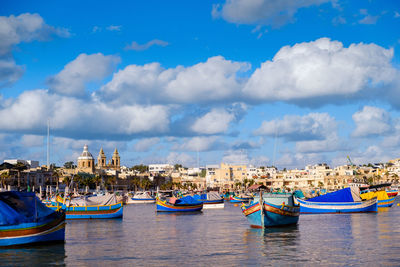 Boats moored in city against blue sky