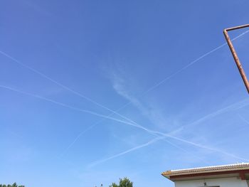 Low angle view of vapor trails against clear blue sky