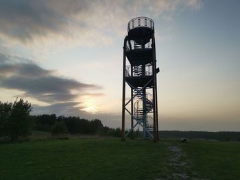 Lifeguard tower on field against sky during sunset