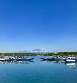 Sailboats moored in sea against blue sky