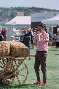 Full length of woman photographing on field