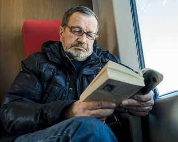 Man reading book while sitting in train