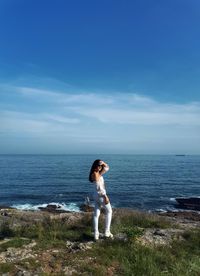 Full length of young woman at beach against sky