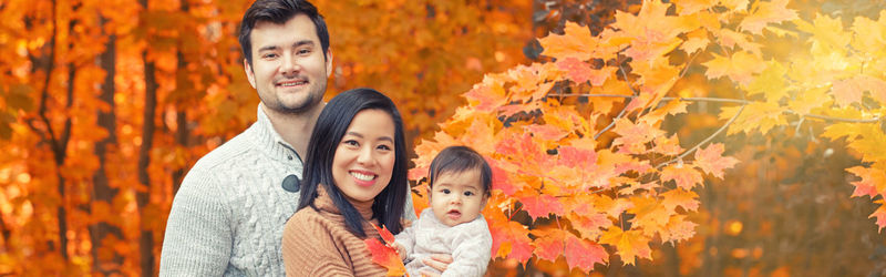 Asian chinese mother and caucasian father dad with baby girl in autumn fall park. family  outdoor 