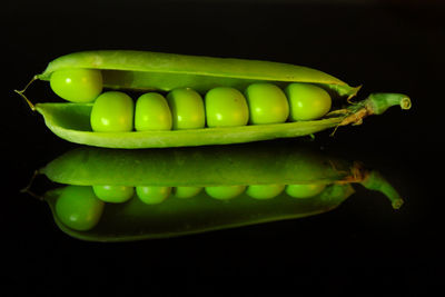 Close-up of green chili pepper on table against black background