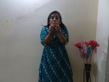 Young woman looking at camera while standing against wall