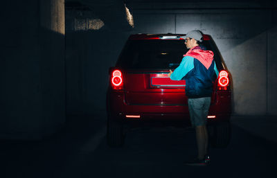 Man by red car in underground parking