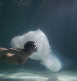 Woman with curtain swimming in pool