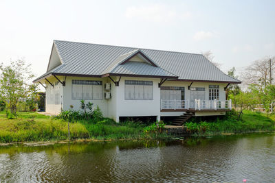 House by lake against sky