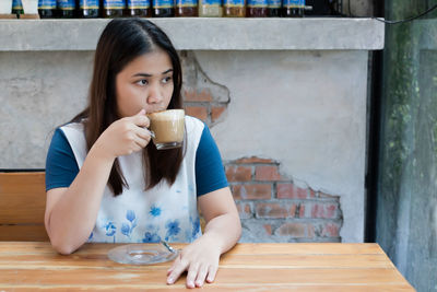 Thoughtful woman having coffee while sitting in cafe