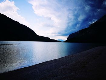 Scenic view of lake by silhouette mountains against sky