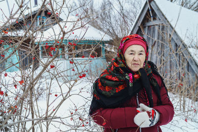 Portrait of woman with red shawl against trees with red berries during winter
