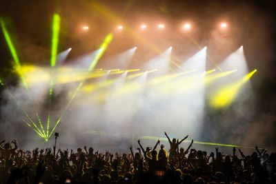 Crowd of people at concert waving hands in air