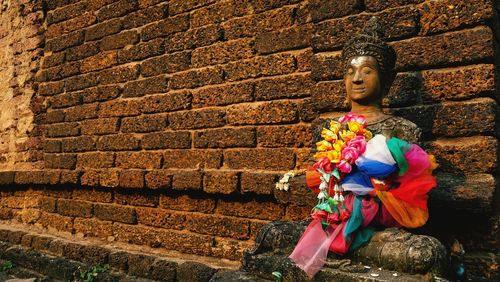 Religious statue by brick wall