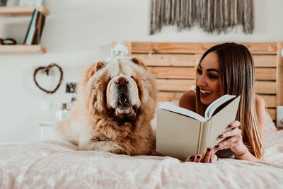 Young woman using mobile phone while relaxing on bed at home