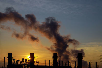 Smoke emitting from factory against sky during sunset