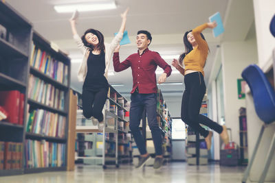 Cheerful friends jumping in library