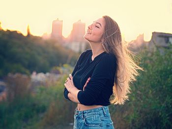 Smiling young woman standing against trees