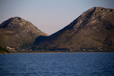 Scenic view of sea and mountains against clear sky