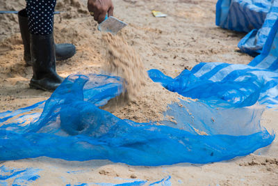 Low section of person cleaning sand at beach