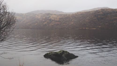 Scenic view of lake by mountains against sky