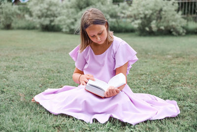 Side view of young woman sitting on field