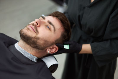 Midsection of female hairdresser cutting man hair in salon