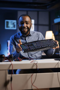 Portrait of young man using laptop at office